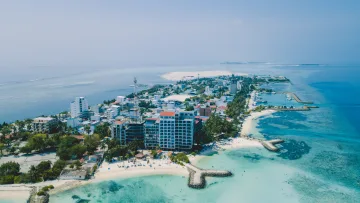 drone-shot, local-island - High altitude aerial drone shot of the local island of Maafushi in the Kaafu Atoll, showcasing hotels and beach.
