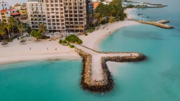 beach, bikini-beach, drone-shot, local-island - Aerial view of a rocky breakwater extending into turquoise water at Maafushi local island in the Kaafu Atoll Maldives
