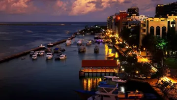 local-island, sunset - Un bellissimo tramonto sul movimentato porto di Male nell'atollo di Kaafu, con motoscafi ormeggiati e luci cittadine.