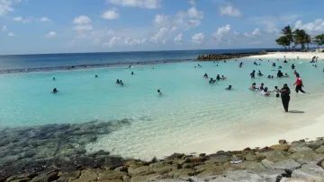 beach, local-island, people - Persone che nuotano e si godono l'acqua turchese nella spiaggia pubblica di Male, atollo di Kaafu, sotto un cielo soleggiato.