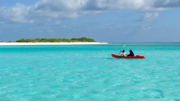 local-island, sea - Coppia che pagaia su un kayak rosso nelle acque turchesi e cristalline dell'isola di Mathiveri, atollo Alifu Alifu.