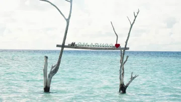 local-island - Wooden sign with hashtag Omadhoo and a red heart submerged in the crystal clear turquoise water of Omadhoo island.