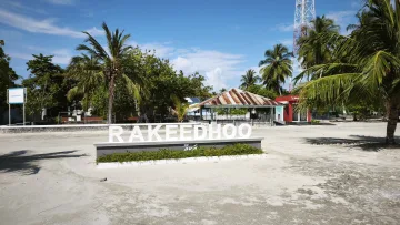local-island - Grande insegna bianca di benvenuto sull'isola di Rakeedhoo, posizionata sulla spiaggia con palme e antenna nell'atollo di Vaavu