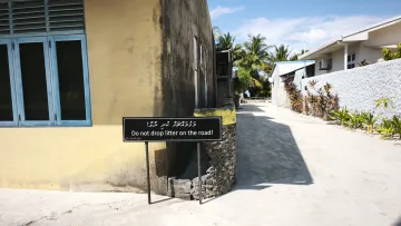 culture, local-island - Un cartello con scritto di non gettare rifiuti sulla strada lungo una via sabbiosa di Rakeedhoo, Atollo di Vaavu.