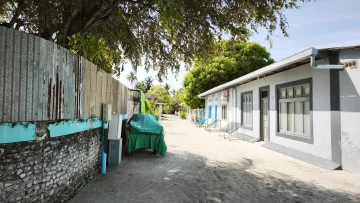 local-island - Una tranquilla strada sabbiosa tra case e muri in pietra sull'isola locale di Rakeedhoo nell'atollo di Vaavu, Maldive.