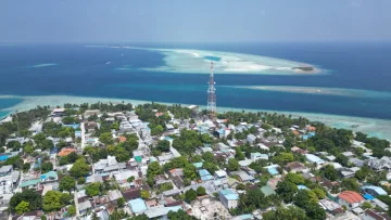 drone-shot, local-island - Aerial view of Rasdhoo local island in Alifu Alifu Atoll with dense houses, green trees and a communication tower.