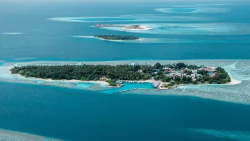 drone-shot, local-island, nature, sea - Drone perspective of Thinadhoo local island in Vaavu Atoll, showing the harbor, lush vegetation, and surrounding reef