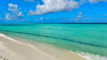 local-island, sea - Una bellissima spiaggia turchese sull'isola locale di Thulusdhoo, atollo di Kaafu, sotto un cielo azzurro e nuvole.