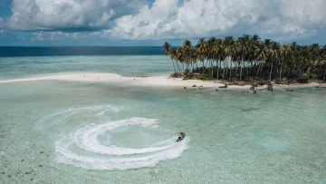 activity, drone-shot, local-island, nature, sea - Vista aerea con drone di una persona su una moto d'acqua che crea una scia circolare vicino alla spiaggia di Thulusdhoo.
