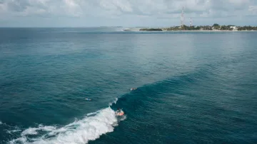 activity, local-island, sea - Surfisti che cavalcano le onde nelle acque cristalline al largo dell'isola di Thulusdhoo nell'atollo di Kaafu.