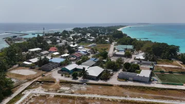drone-shot, local-island - Drone aerial view of the local island of Vashafaru in Haa Alifu Atoll, showing homes, lush vegetation, and beaches.