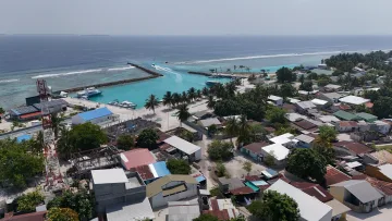 drone-shot, local-island - Aerial view of Vashafaru local island harbor in Haa Alifu Atoll with boats, breakwater, and residential village