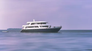 luxury, sunset - Un moderno yacht di lusso bianco naviga attraverso l'oceano calmo sotto un soffice cielo viola al tramonto alle Maldive