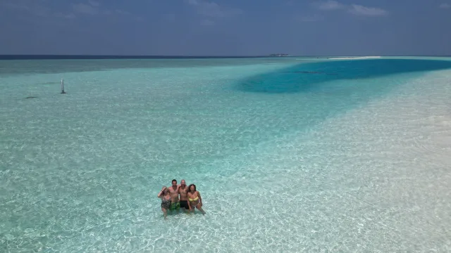 drone-shot, people, sea - A group of four friends standing in the crystal clear turquoise water of Madivaru near Rasdhoo atoll in Maldives.
