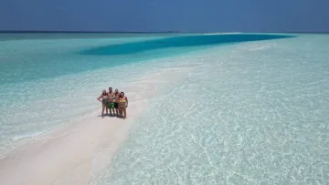 Aerial view of a group of friends standing on the white Madivaru sandbank near Rasdhoo island, Alifu Alifu Atoll.