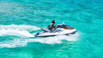 activity, sea - An adventurous traveler riding a jet ski across the vibrant turquoise ocean water during a sunny tropical day.
