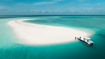 activity, drone-shot, nature, sea - A private boat docked at a white sandbank surrounded by vibrant turquoise shallow water under a clear blue sky