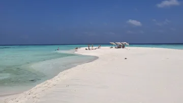 beach, people, relax - Group of tourists relaxing under umbrellas on a pristine white sandbank surrounded by a crystal clear turquoise lagoon