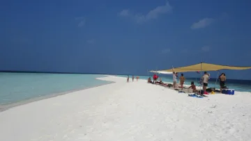 beach, people, relax, sea - Tourists relaxing under shaded canopy tents on a pristine white sandbank surrounded by turquoise ocean waters.