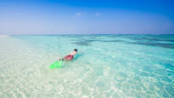 activity, sea, snorkeling - Una persona che fa snorkeling in una laguna tropicale turchese e poco profonda con fondale sabbioso e cielo azzurro.