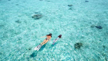 activity, sea, snorkeling, sky - Una donna e una bambina fanno snorkeling in una laguna turchese cristallina sotto un cielo azzurro con nuvole leggere
