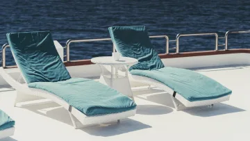 luxury, relax - Due lettini prendisole con cuscini blu e un tavolino bianco sul ponte di uno yacht che si affaccia sul mare blu profondo.