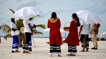 culture, people - Gruppo di artisti in abiti tradizionali con tamburi e ombrelli bianchi su una spiaggia di sabbia bianca alle Maldive