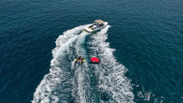 activity, drone-shot, sea - Veduta aerea di un motoscafo che traina una turista su un gommone giallo e uno rosso nelle blu acque dell'oceano.
