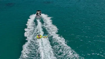 activity, drone-shot, sea - Vista aerea di un motoscafo che traina due persone su gommoni gonfiabili nel mare turchese cristallino tropicale