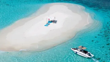 beach, luxury, relax, sea - Aerial view of a pristine white sand beach meeting a vibrant turquoise lagoon with a sunbathing canopy and lounge chairs