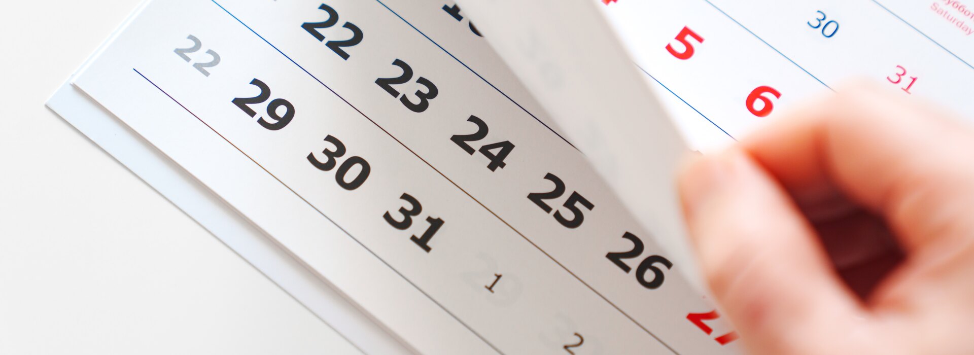 Una mano che gira le pagine di un calendario per scegliere le date di una perfetta vacanza tropicale di lusso.