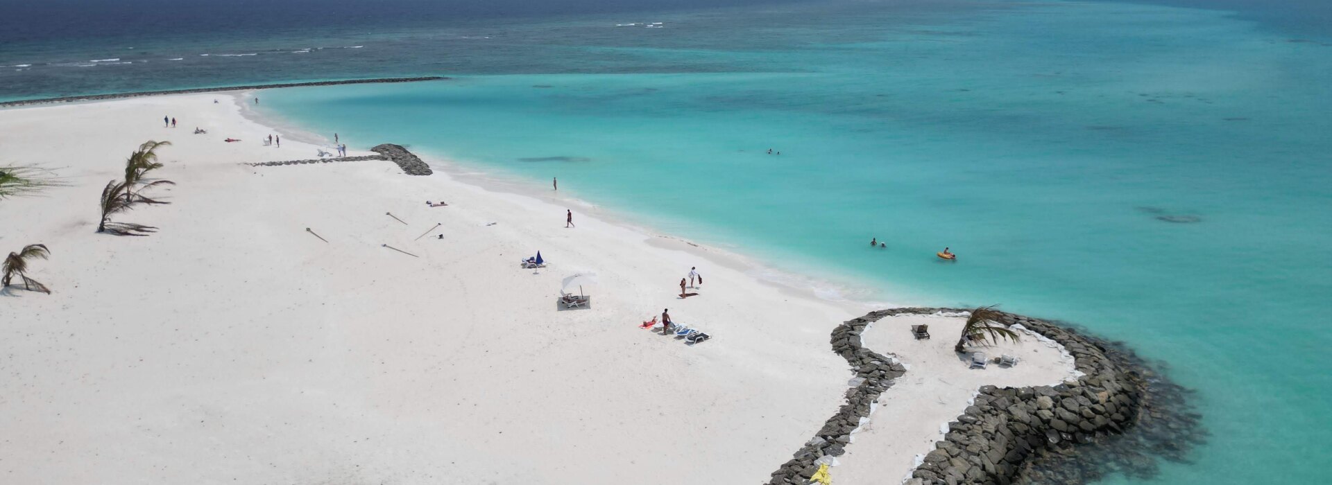 Veduta aerea della spiaggia di sabbia bianca e laguna turchese a Fulidhoo, atollo di Vaavu, con turisti che si rilassano.