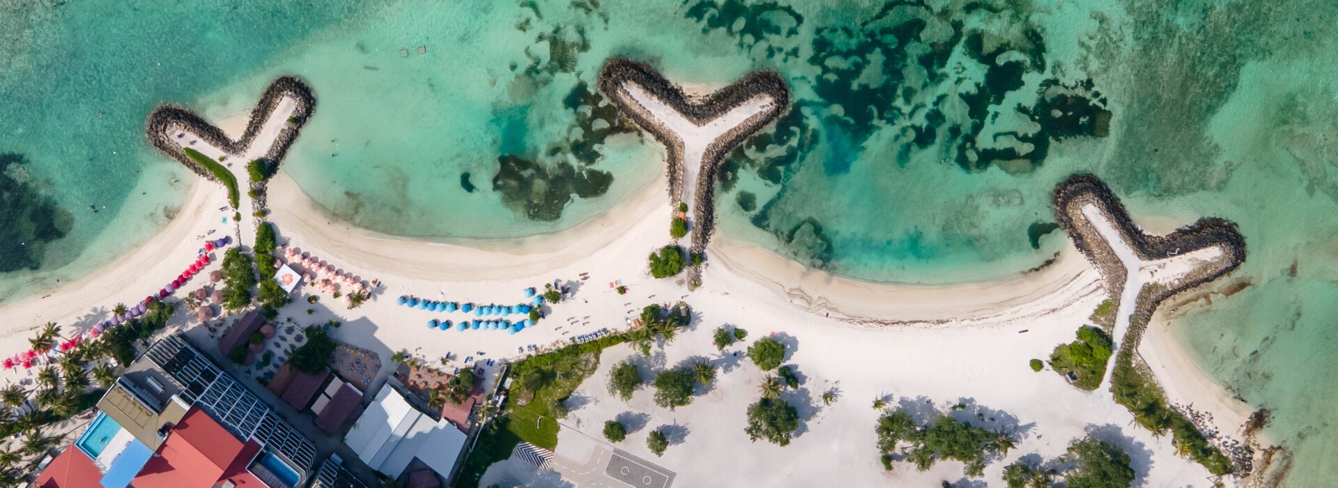 Aerial view of the Bikini Beach on Maafushi local island in the Kaafu Atoll, featuring turquoise sea and breakwaters
