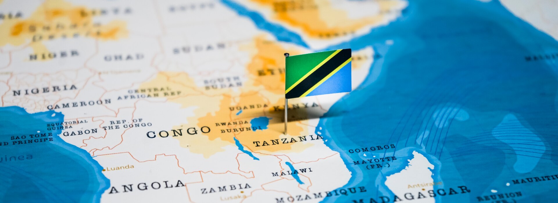 Small flag of Tanzania pinned on a geographical map of Africa, centered on the Tanzanian territory.
